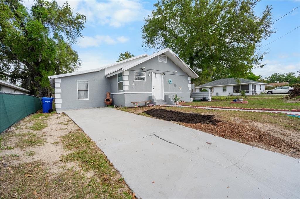 A gray single-story house with a concrete driveway and a white front door — 221 AVENUE L NE, WINTER HAVEN, FL