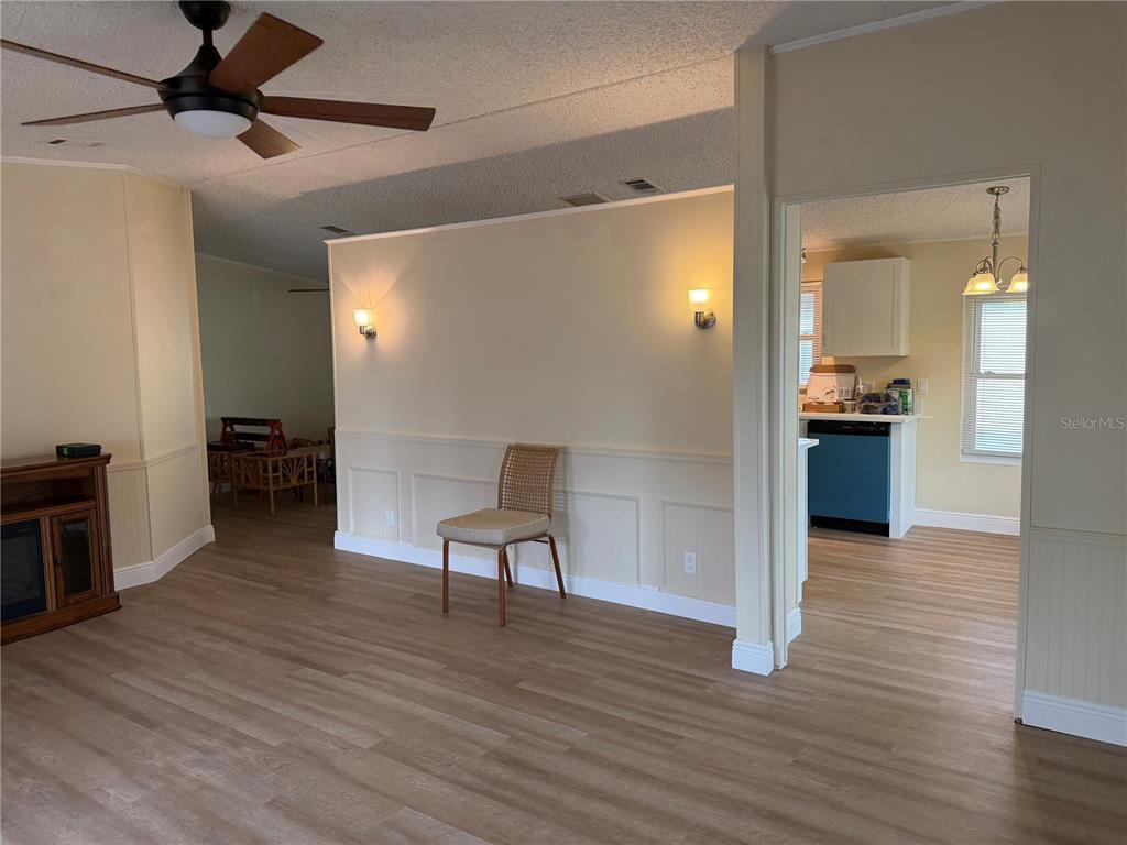 A single-story tan mobile home with a carport and a front lawn under a blue sky — 1676 ELKHART CIRCLE, TAVARES, FL