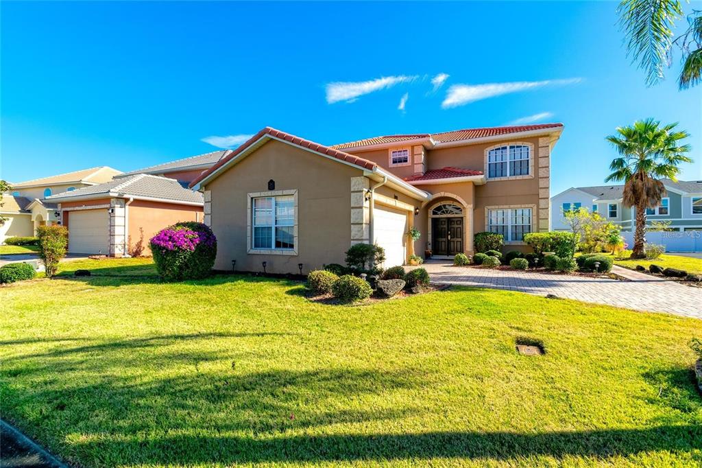 A two-story suburban house with a tan stucco exterior, a tiled roof, and a front lawn — 284 VISTA DRIVE, DAVENPORT, FL
