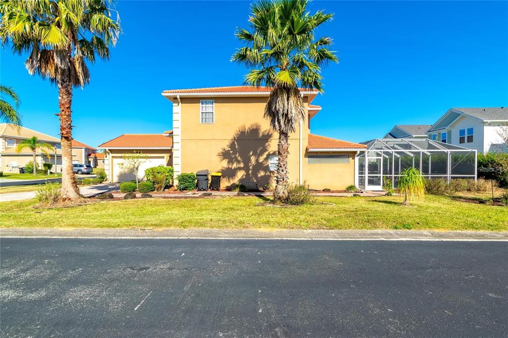 A two-story tan house with a tile roof, palm trees, and a screened-in pool enclosure — 284 VISTA DRIVE, DAVENPORT, FL