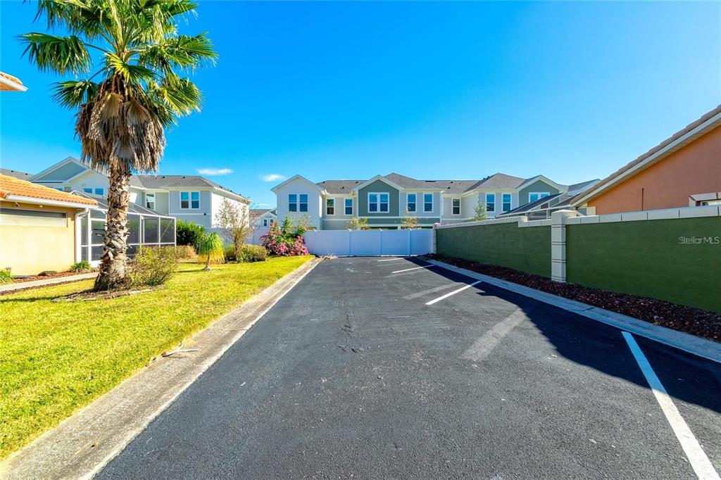 An asphalt parking area sits between a grassy yard with a palm tree and a wall — 284 VISTA DRIVE, DAVENPORT, FL