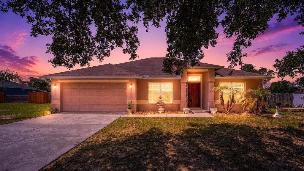 A single-story house with a two-car garage and a front yard at sunset — 537 HATCHWOOD DRIVE, HAINES CITY, FL