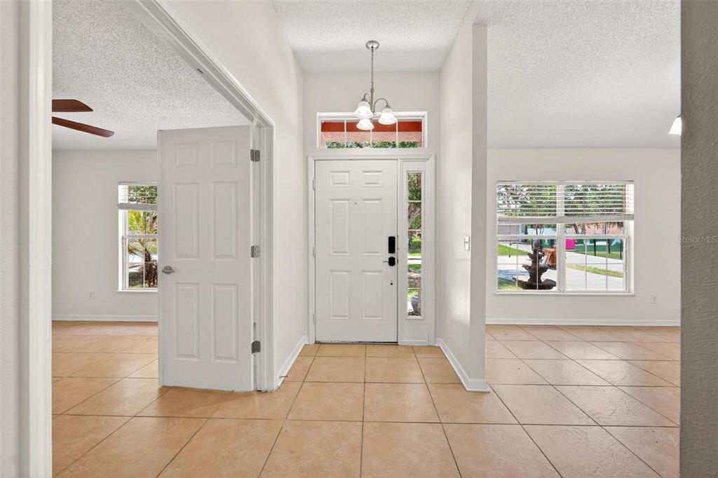 An entryway with tan tile flooring, a white front door, and a hanging light fixture — 537 HATCHWOOD DRIVE, HAINES CITY, FL