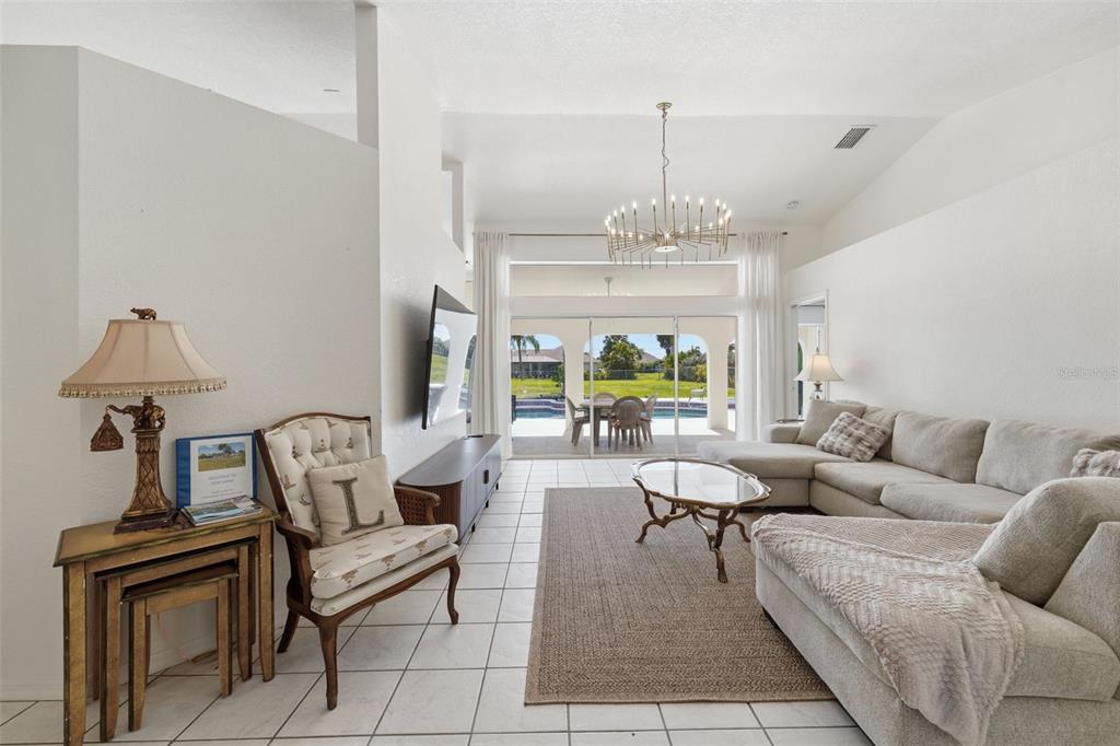 A living room with tile floors, a sectional sofa, and sliding doors opening to a pool — 275 ROTONDA BOULEVARD N, ROTONDA WEST, FL