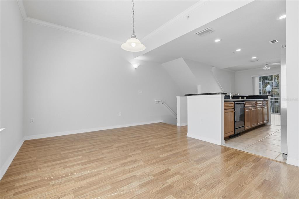 An open-concept dining area with light wood flooring leads to a kitchen with wooden cabinets — 9875 MEADOW FIELD CIRCLE, TAMPA, FL