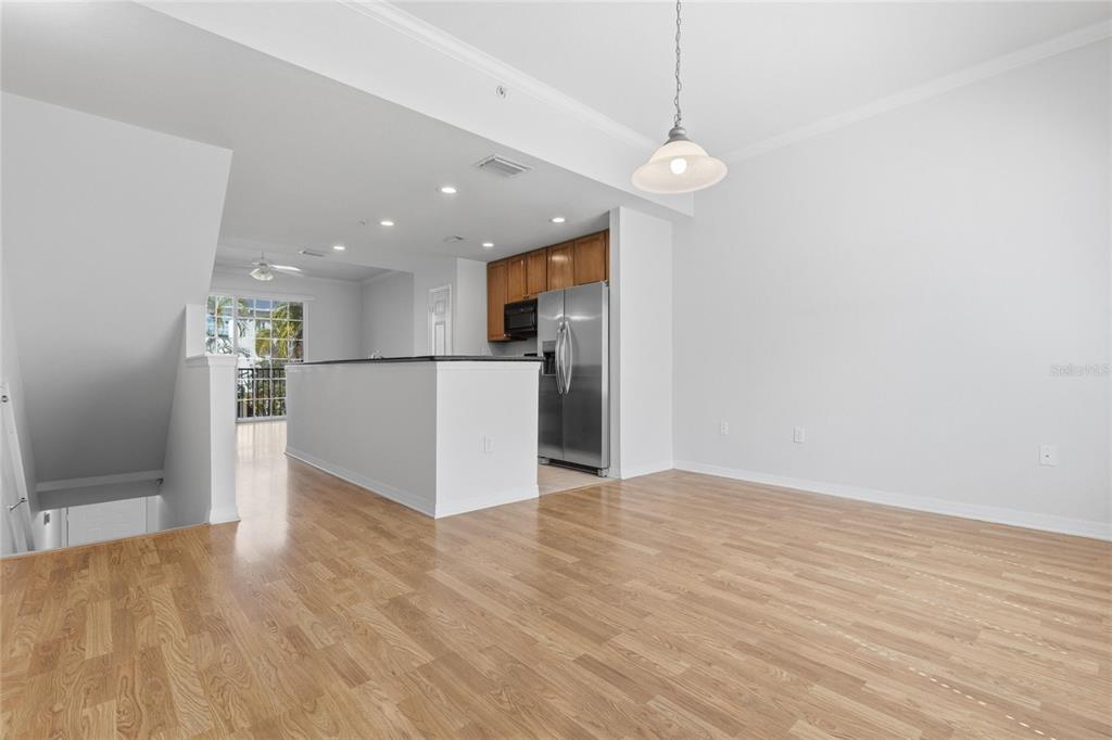 An open-concept kitchen with stainless steel appliances overlooks a living area with wood flooring — 9875 MEADOW FIELD CIRCLE, TAMPA, FL