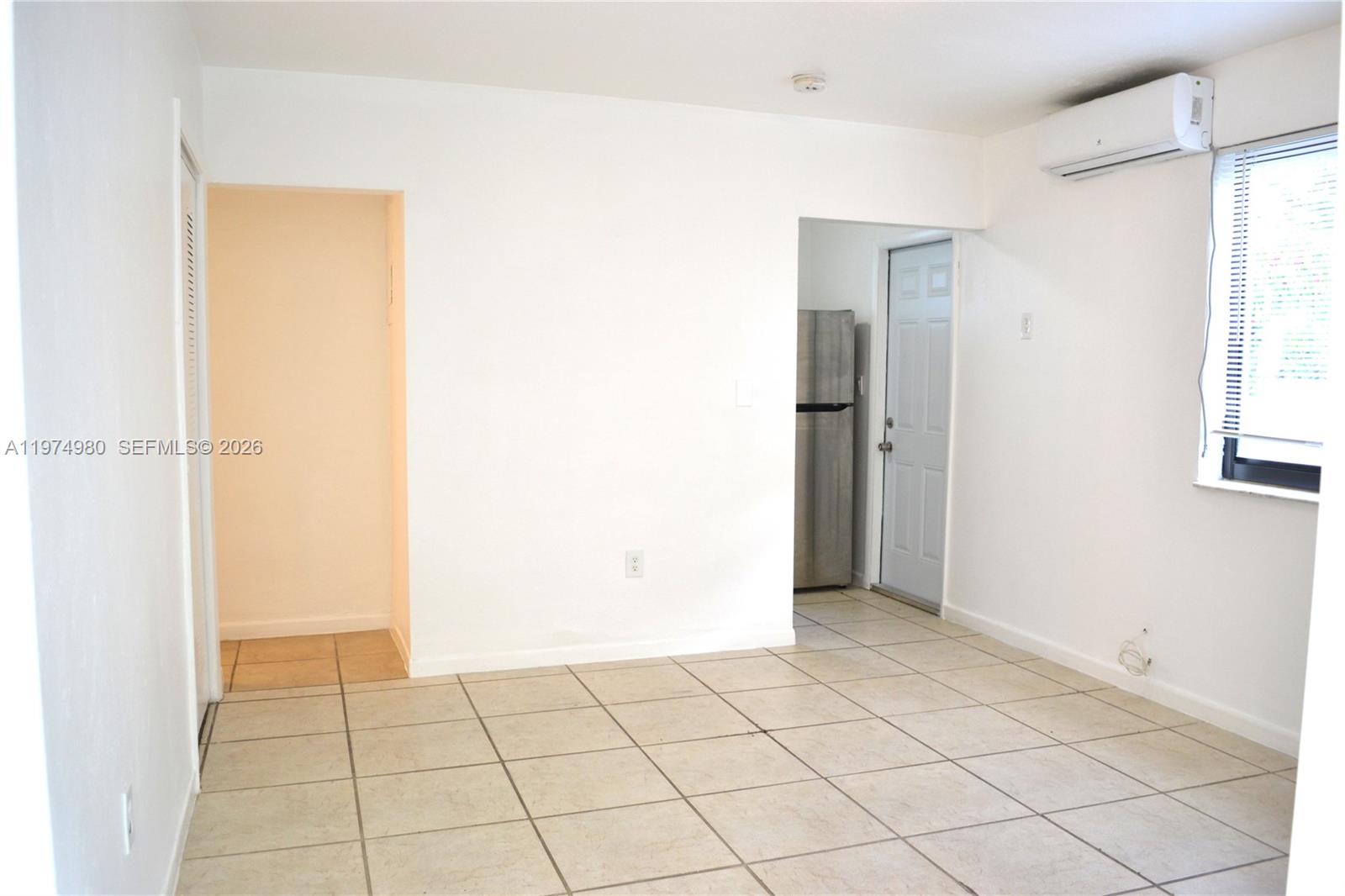 A room with white walls, tiled floors, a window, and a doorway to a kitchen — 1035 SW 4th St # 2, Miami FL 33130, MIAMI, FL