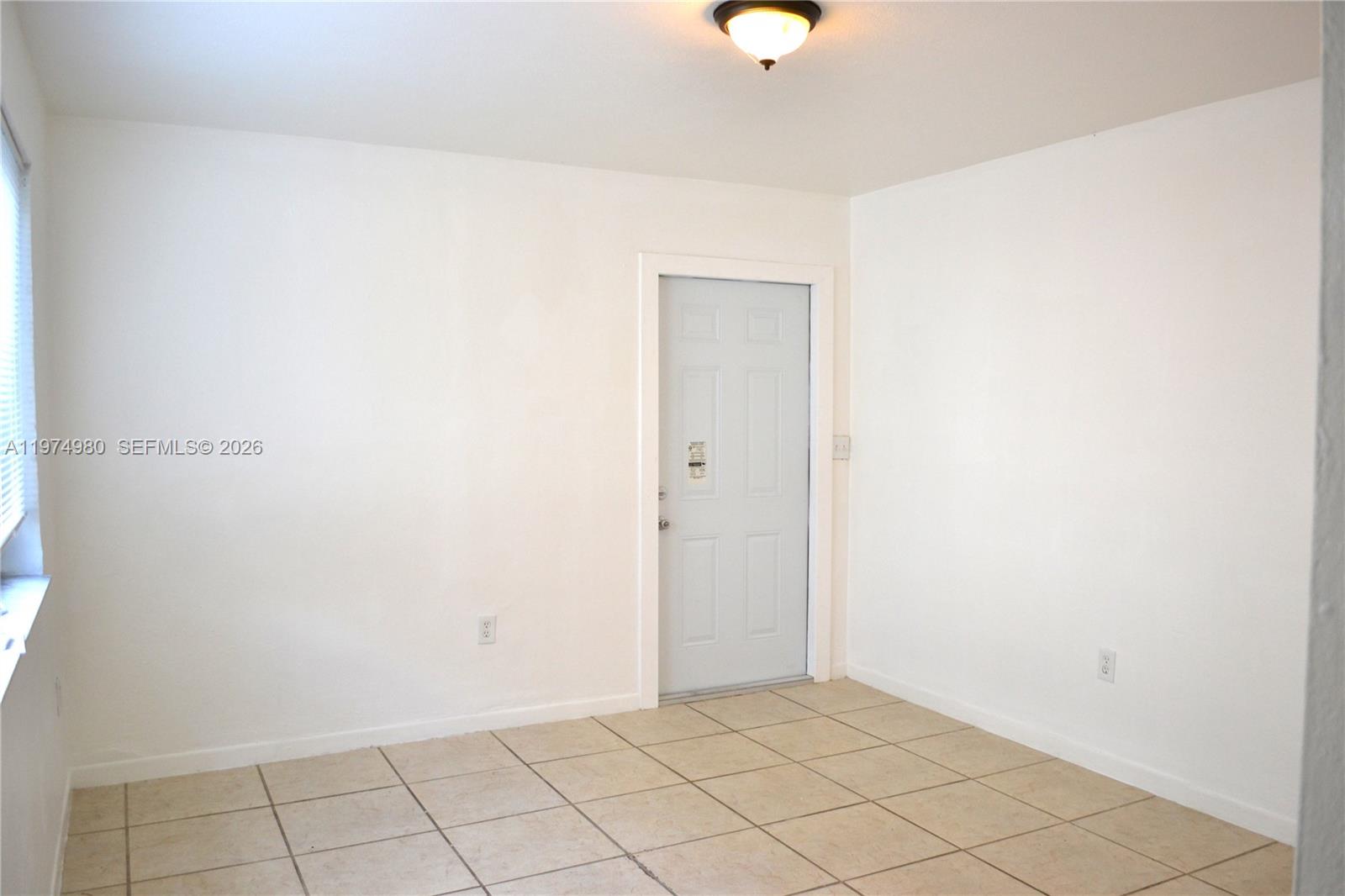A room with white walls, tiled flooring, a single door, and a ceiling light fixture — 1035 SW 4th St # 2, Miami FL 33130, MIAMI, FL