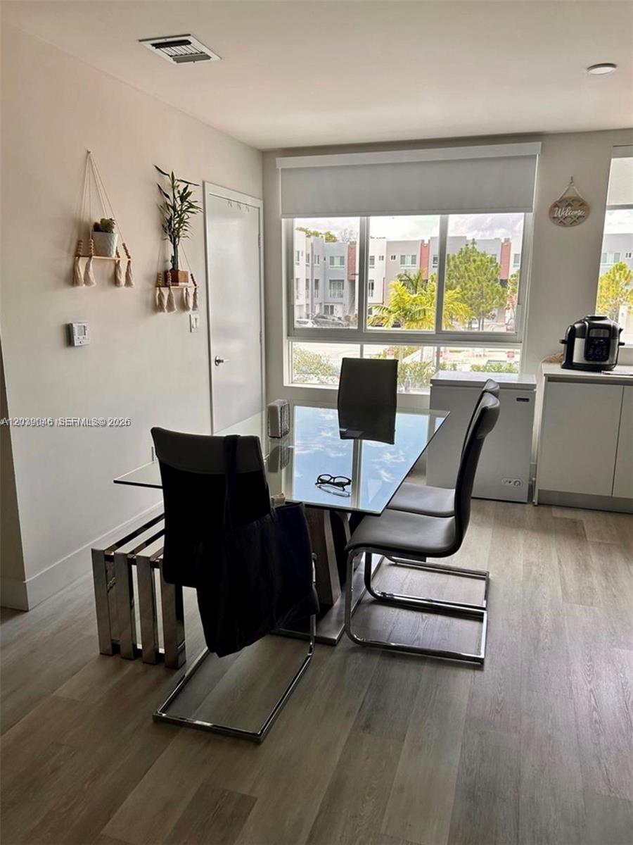 A dining area features a glass table, modern chairs, and a large window with blinds — 2561 NE 193rd St # 1201, Miami FL 33180, MIAMI, FL
