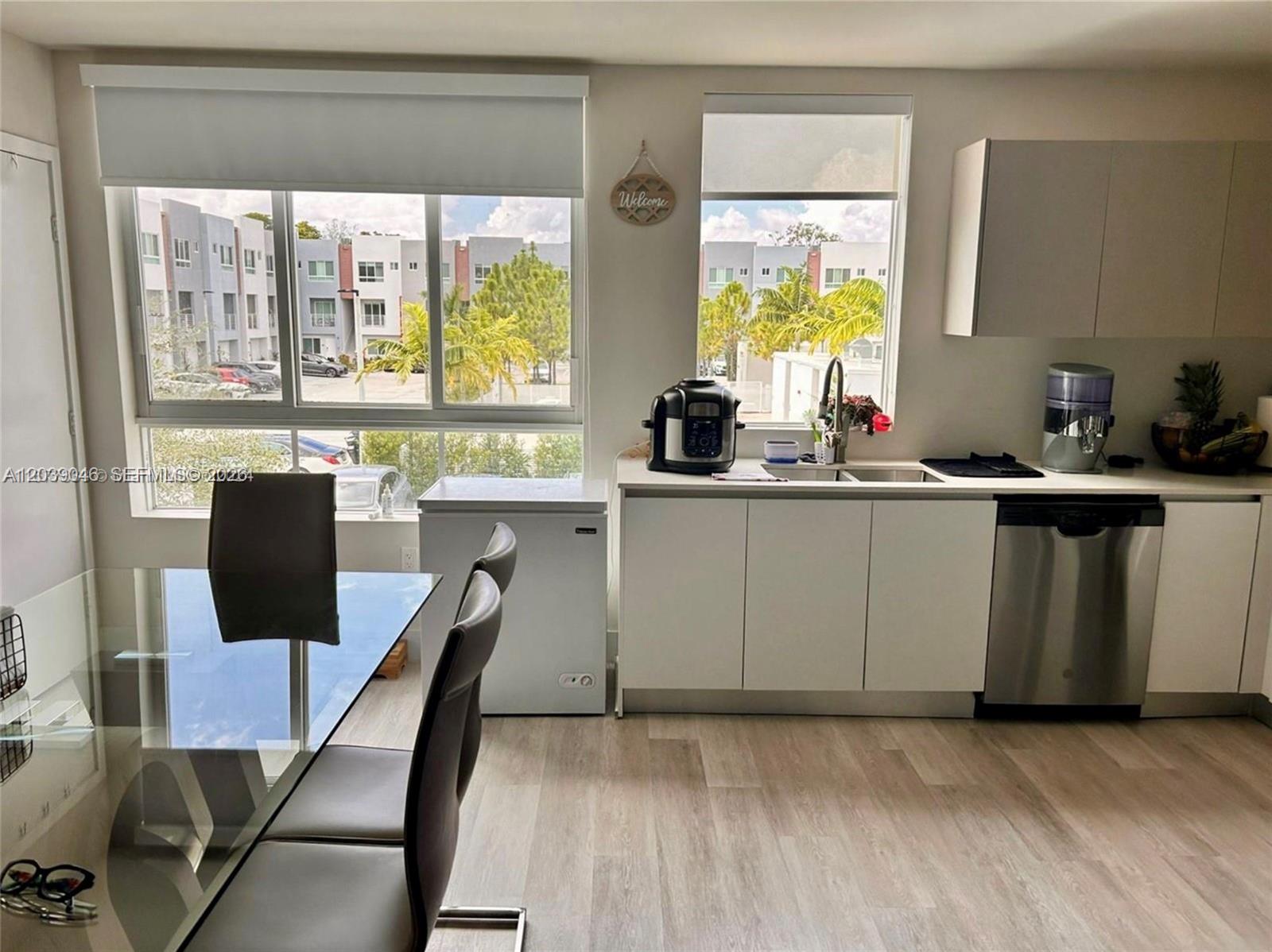 A kitchen with white cabinets, stainless steel appliances, and a dining table by a window — 2561 NE 193rd St # 1201, Miami FL 33180, MIAMI, FL