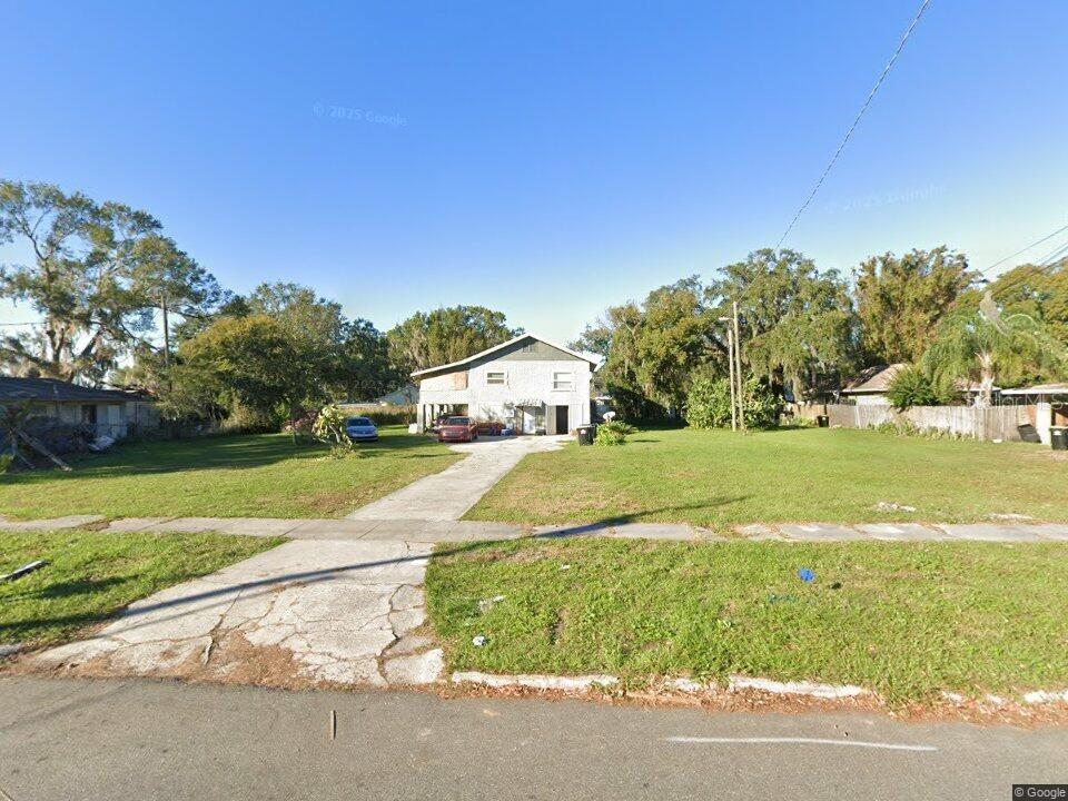 A two-story house with a concrete driveway sits on a large, grassy residential lot — 730 VIRGINIA AVENUE, AUBURNDALE, FL