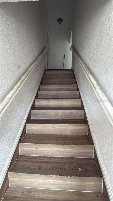 A straight staircase with wood-look treads and white walls leads to an upper landing — 730 VIRGINIA AVENUE, AUBURNDALE, FL