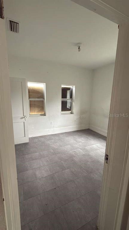 An empty room with gray tile flooring, white walls, and two windows — 730 VIRGINIA AVENUE, AUBURNDALE, FL