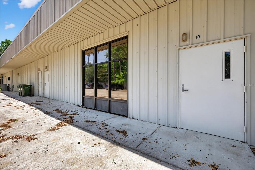 The exterior of a commercial building features a white metal facade, a glass window, and a door — 1314 SUMTER STREET, LEESBURG, FL