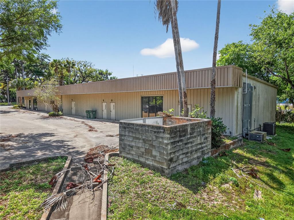A single-story commercial building with metal siding and a concrete block dumpster enclosure outside — 1314 SUMTER STREET, LEESBURG, FL