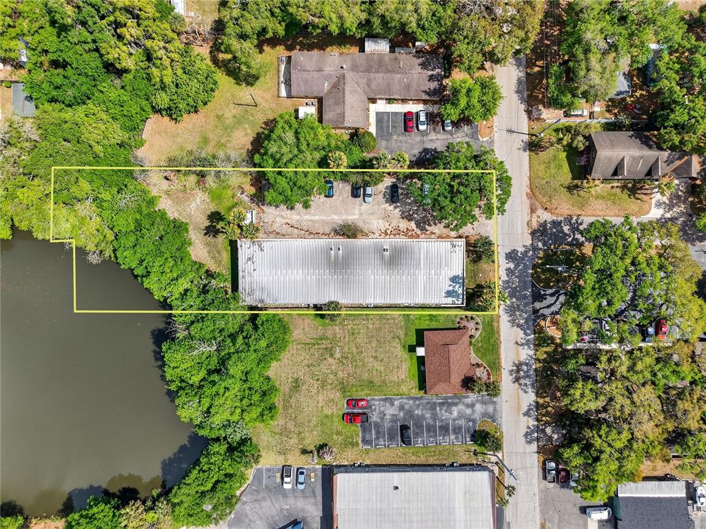 An aerial view shows a commercial building with a parking lot next to a lake — 1314 SUMTER STREET, LEESBURG, FL