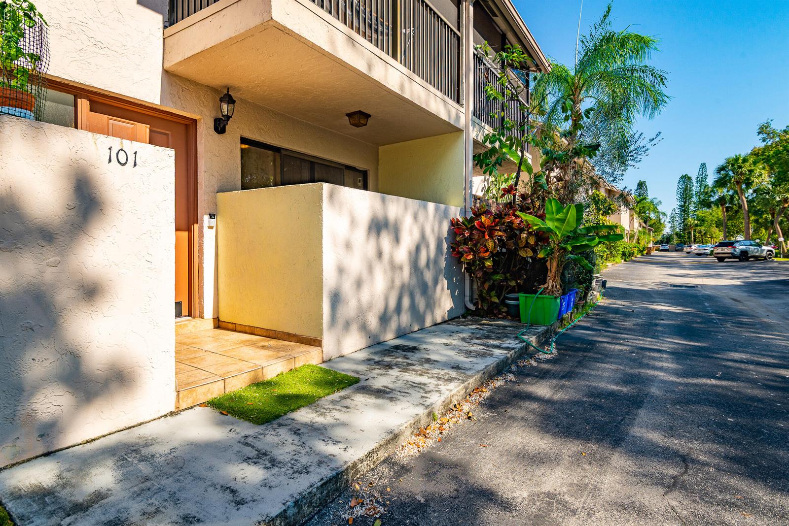 A ground-level apartment entrance with a tiled porch, a small privacy wall, and landscaping — 740 SE 1st Way # 101, Deerfield Beach FL 33441, DEERFIELD BEACH, FL