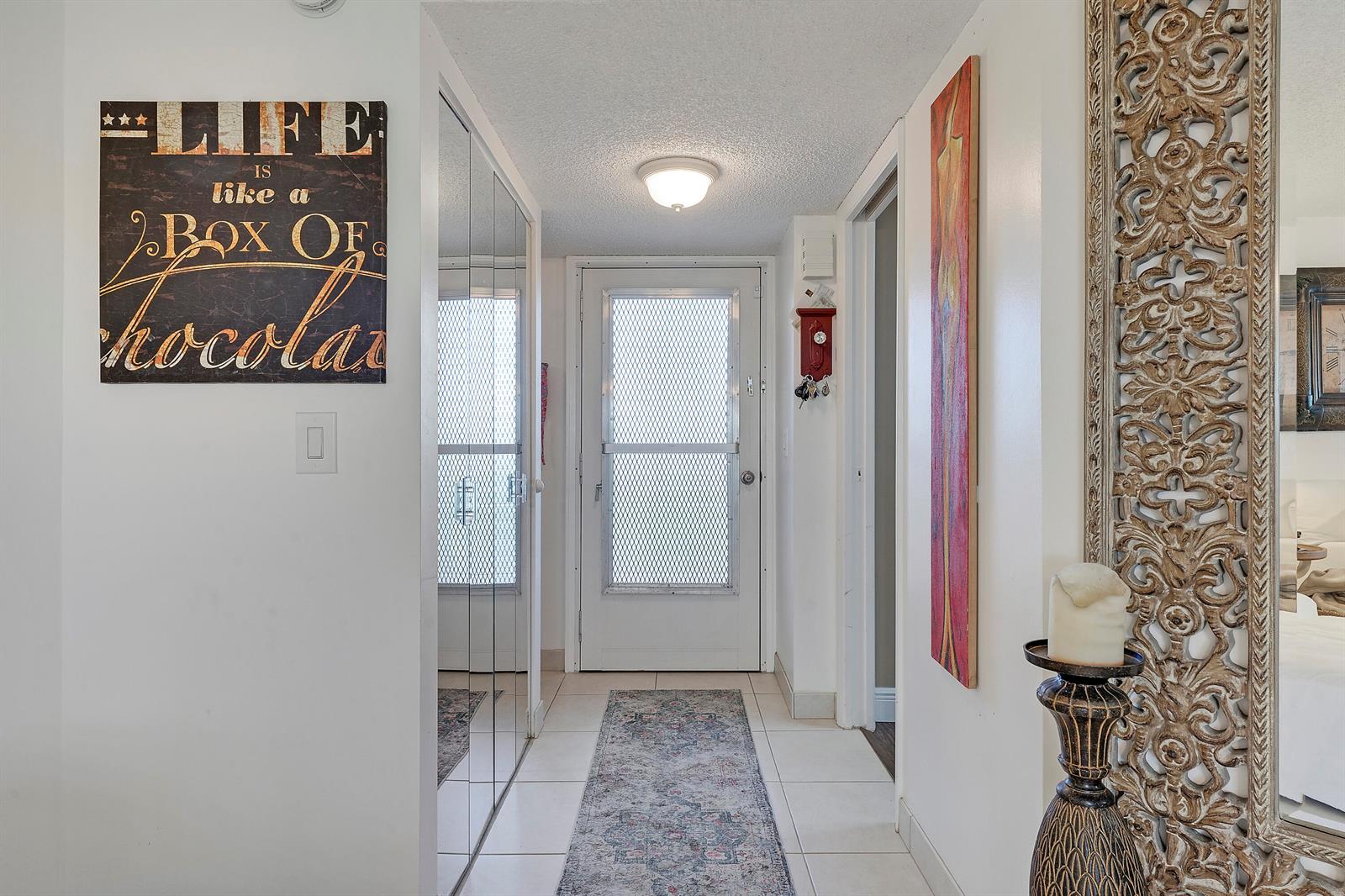 A hallway features white tile floors, a mirrored closet, a front door, and wall art — 3755 Via Poinciana, FL 33467, FL