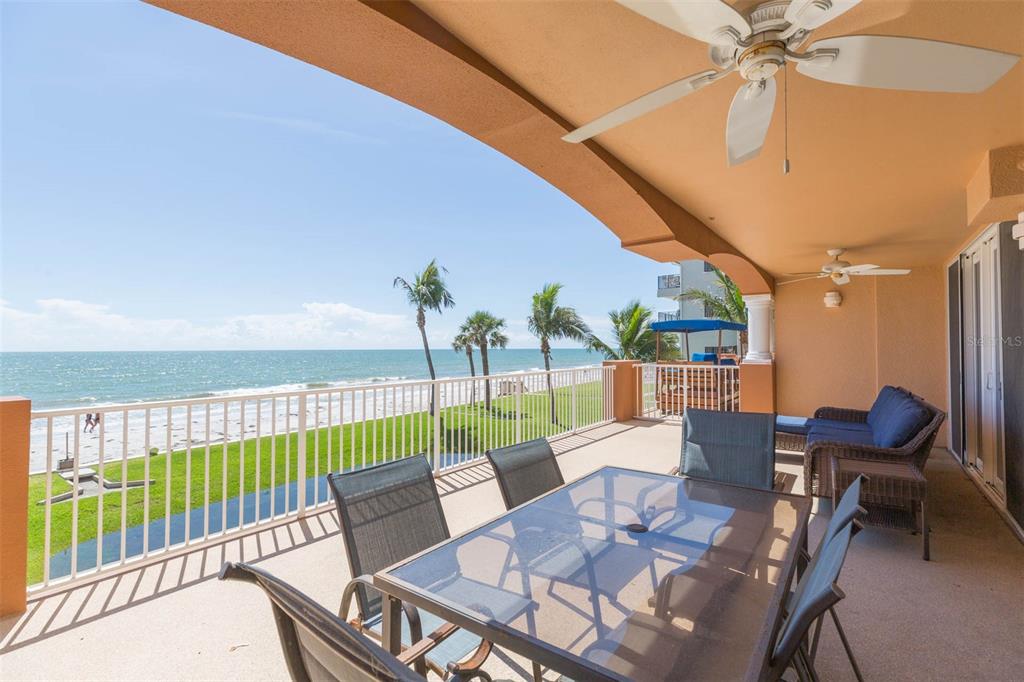 A covered balcony features outdoor dining furniture and seating overlooking a beach and the ocean — 16326 GULF BOULEVARD UNIT 109, REDINGTON BEACH, FL
