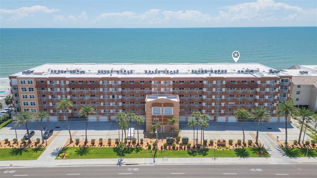 An aerial view of a multi-story apartment building situated directly along a sandy beach — 16326 GULF BOULEVARD UNIT 109, REDINGTON BEACH, FL