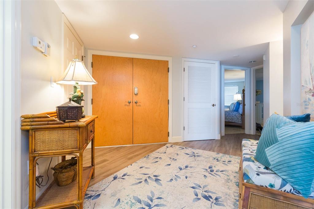 A hallway features wood-look flooring, a patterned area rug, double wood doors, and a console table — 16326 GULF BOULEVARD UNIT 109, REDINGTON BEACH, FL