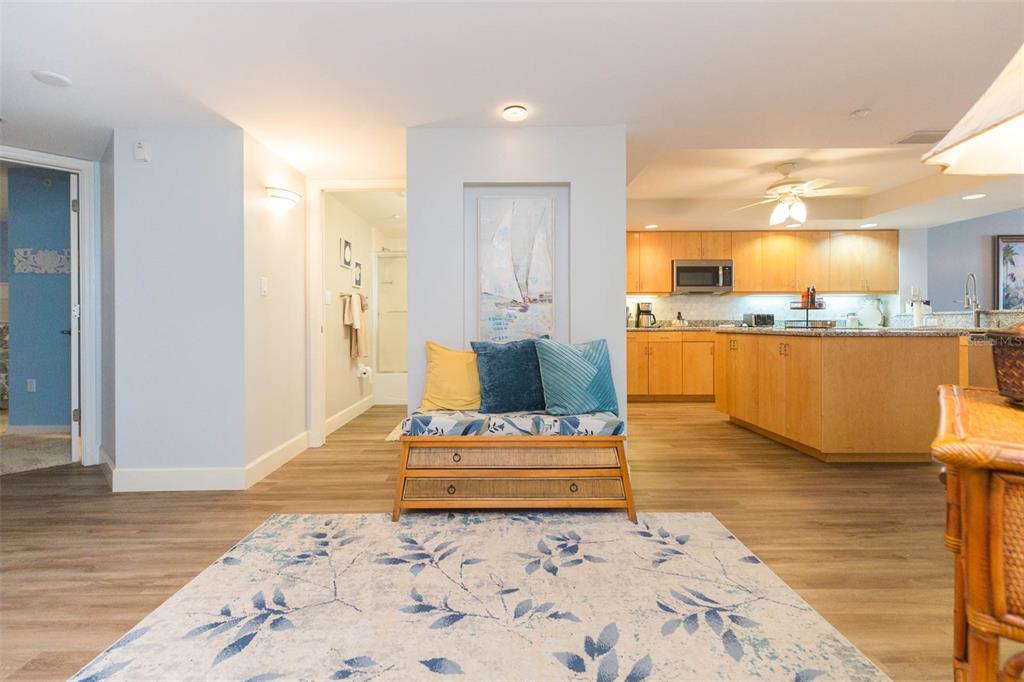 A living area with a bench, a patterned rug, and an open kitchen with cabinets — 16326 GULF BOULEVARD UNIT 109, REDINGTON BEACH, FL