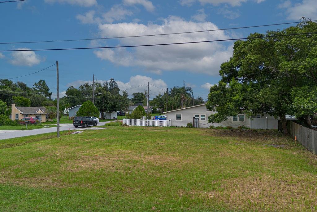 A vacant grassy lot sits in front of a residential street with houses and trees — 5102 SUNRISE BOULEVARD, ORLANDO, FL