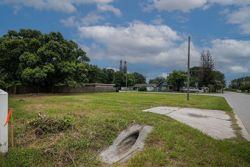 A vacant grassy lot features a concrete driveway apron and a storm drain inlet — 5102 SUNRISE BOULEVARD, ORLANDO, FL