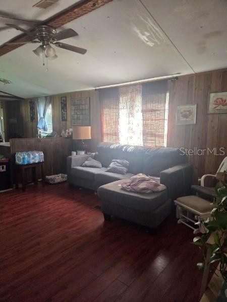 A living room features wood-paneled walls, a gray sectional sofa, and dark wood-look flooring — 3563 SE 147TH PLACE, SUMMERFIELD, FL