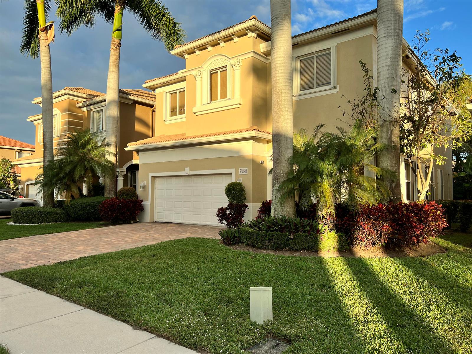 A two-story tan stucco house with a two-car garage and palm trees in the front yard — 4350 Key Lime Boulevard, Boynton Beach FL 33436, BOYNTON BEACH, FL