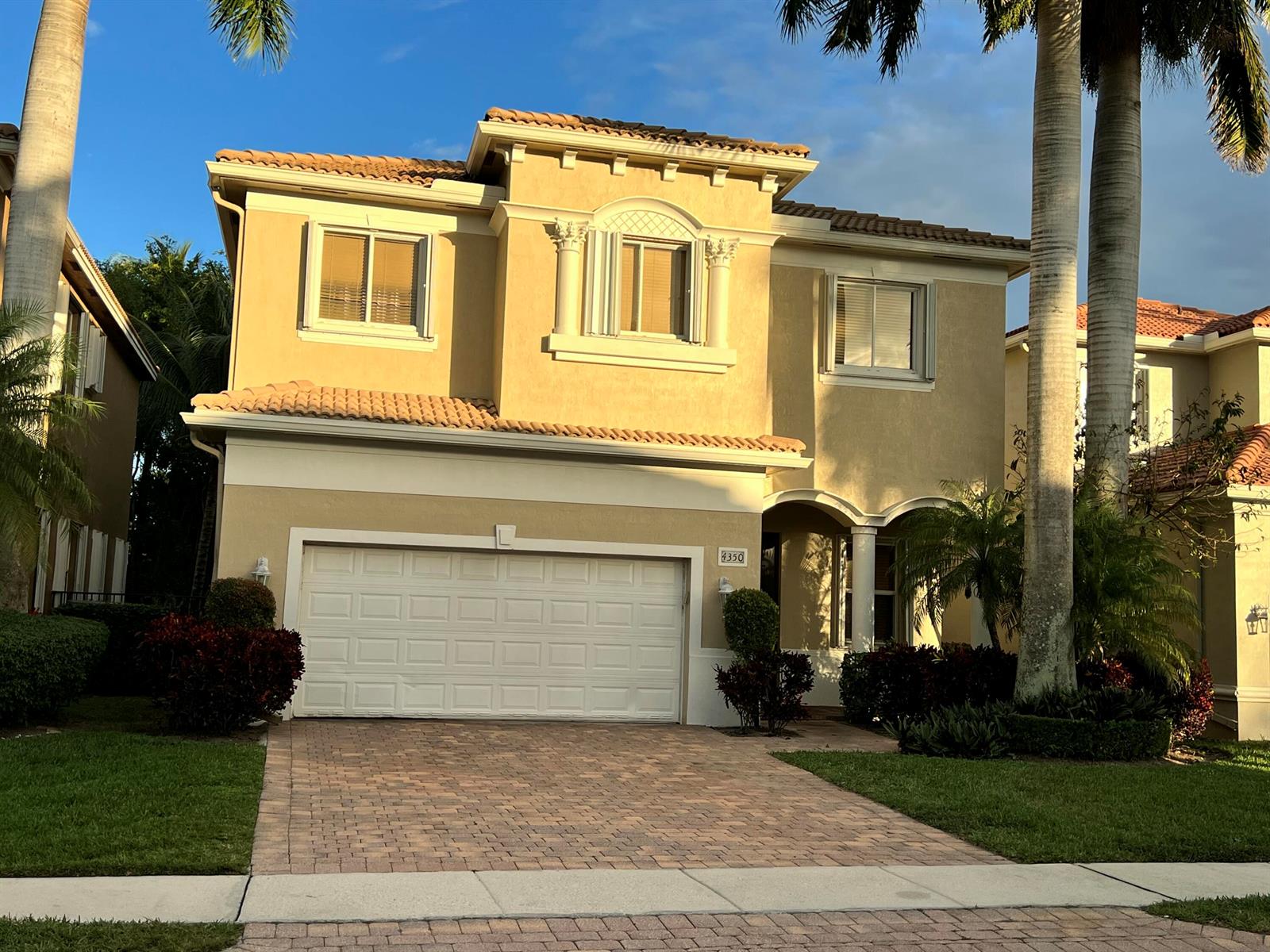 A two-story tan stucco house with a tiled roof, a two-car garage, and palm trees — 4350 Key Lime Boulevard, Boynton Beach FL 33436, BOYNTON BEACH, FL