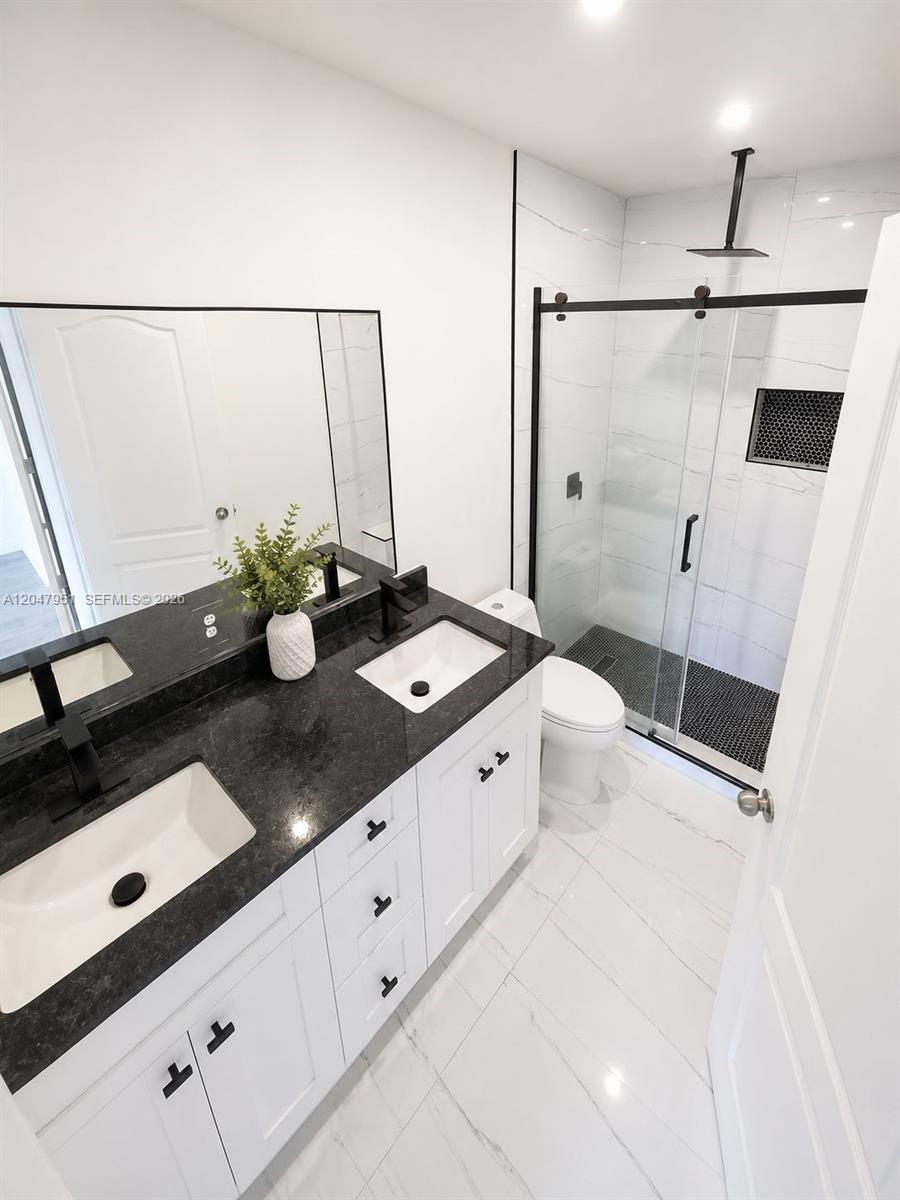 A kitchen with wood cabinets and quartz countertops overlooks an open-concept living area with tile floors — 3092 SW 129th Ter # 102, Miramar FL 33027, MIRAMAR, FL