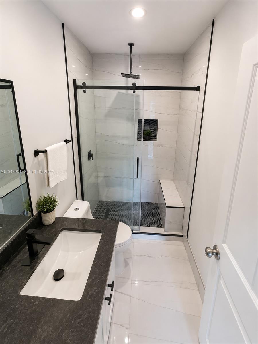 A modern bathroom features a white double vanity with a black countertop and a glass-enclosed shower — 3092 SW 129th Ter # 102, Miramar FL 33027, MIRAMAR, FL