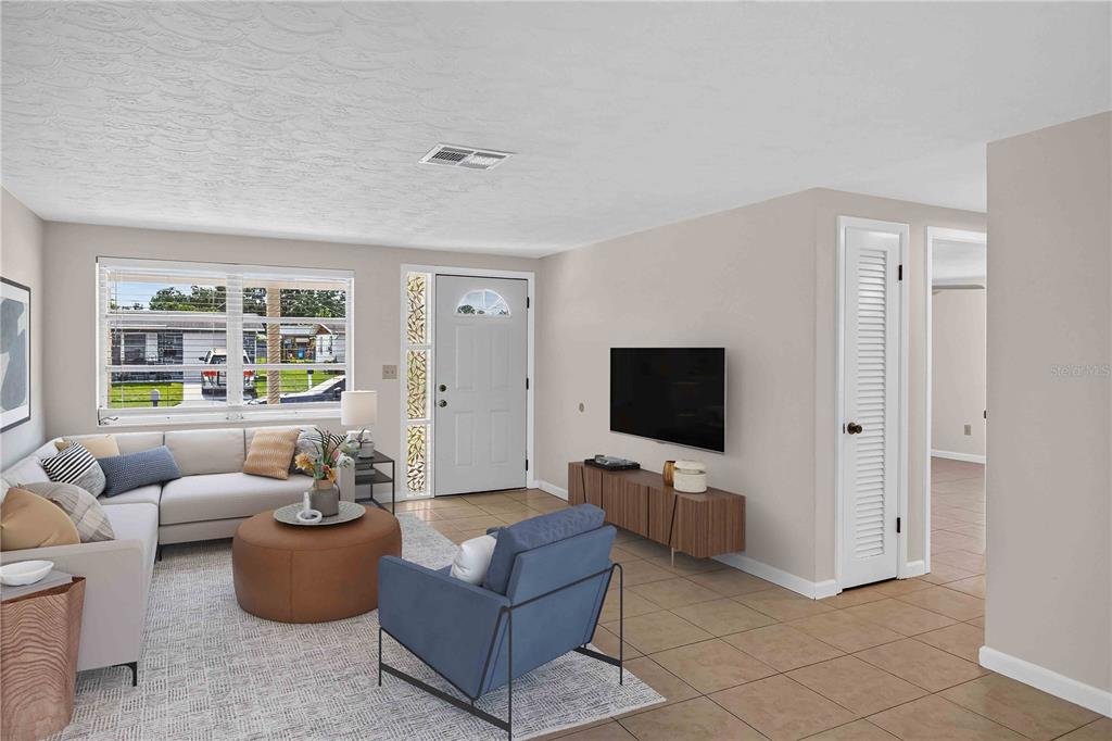 A living room features a sectional sofa, blue armchair, television, and tile flooring — 2044 PAMELA DRIVE, HOLIDAY, FL