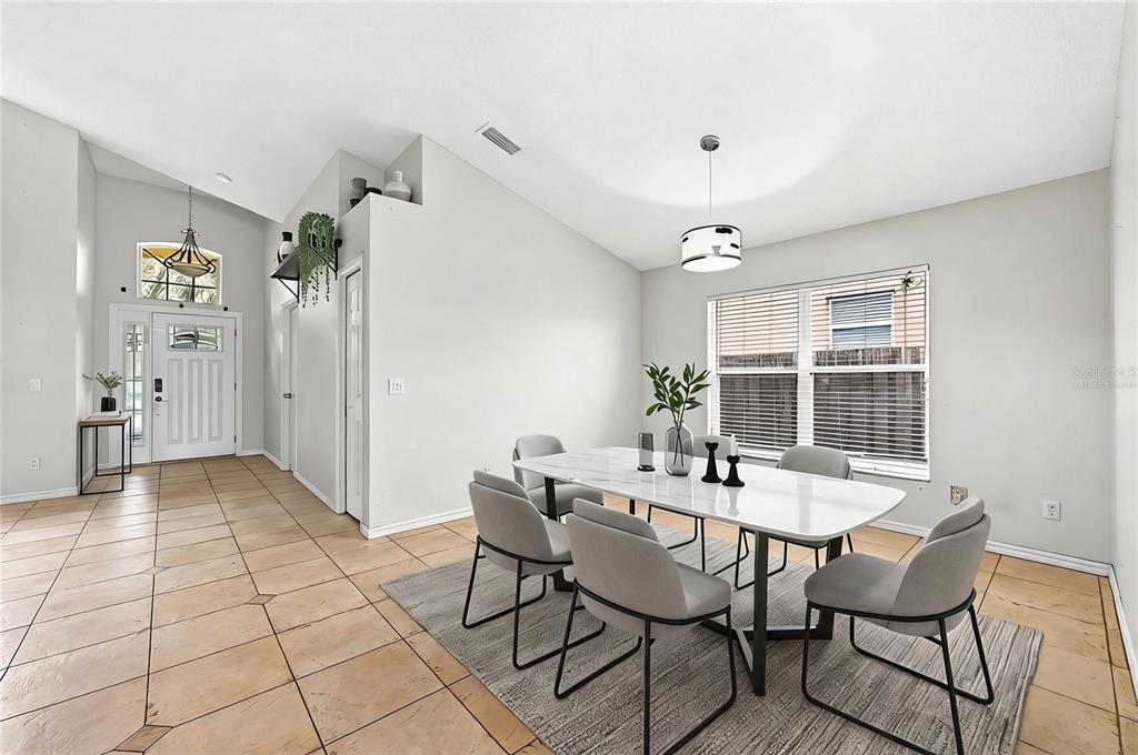 A dining room with a white table, gray chairs, tile flooring, and a vaulted ceiling — 2551 WALNUT HEIGHTS ROAD, APOPKA, FL