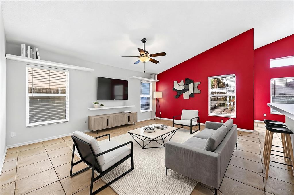 A living room features a vaulted ceiling, a red accent wall, and tiled flooring — 2551 WALNUT HEIGHTS ROAD, APOPKA, FL