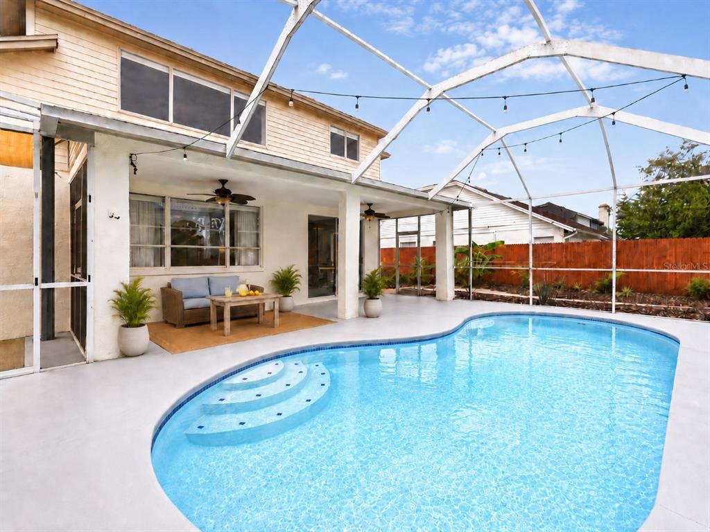 A backyard swimming pool with a screened enclosure, patio furniture, and a two-story house — 1610 LEDGESTONE DRIVE, BRANDON, FL