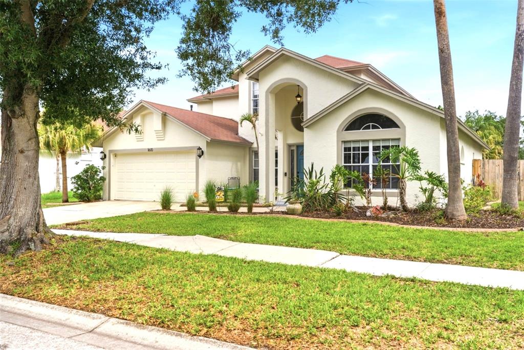 A two-story house with a beige stucco exterior, a two-car garage, and a front lawn — 1610 LEDGESTONE DRIVE, BRANDON, FL