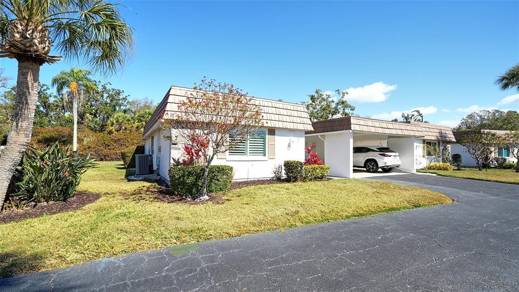 A white single-story house with a carport and a palm tree in the front yard — 5469 RIVERBLUFF CIRCLE UNIT 42, SARASOTA, FL