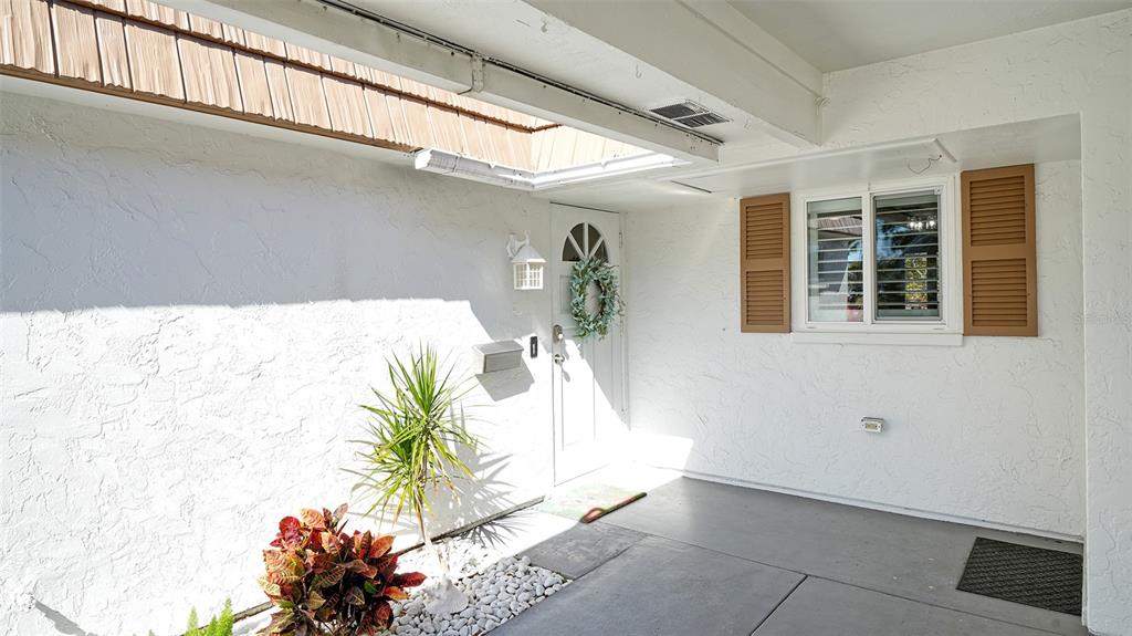 A covered entryway features a white front door, a window with brown shutters, and landscaping — 5469 RIVERBLUFF CIRCLE UNIT 42, SARASOTA, FL