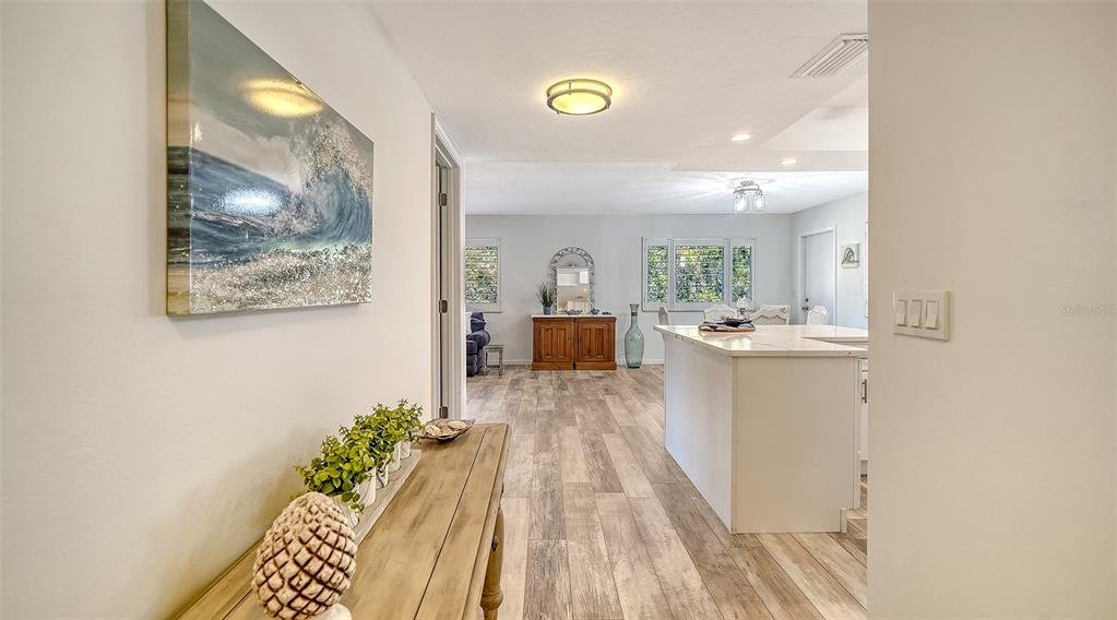 A hallway with a console table leads into an open-concept kitchen and living area — 5469 RIVERBLUFF CIRCLE UNIT 42, SARASOTA, FL