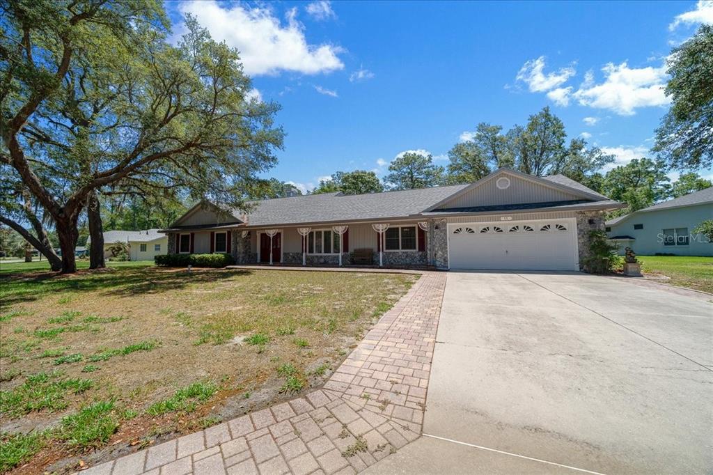 A single-story house with a stone facade, a two-car garage, and a paved driveway — 11 SYCAMORE COURT W, HOMOSASSA, FL