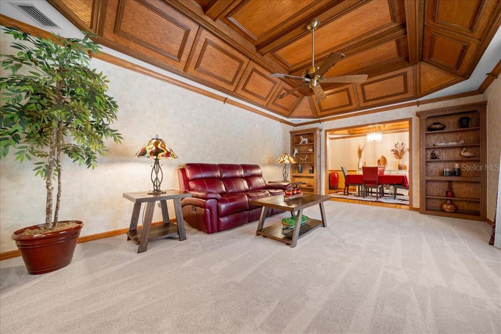 A living room with a coffered wood ceiling, red leather sofa, and built-in shelving — 11 SYCAMORE COURT W, HOMOSASSA, FL