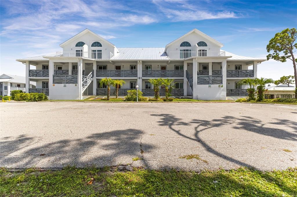 A two-story white apartment building with a metal roof and a large paved parking lot — 6800 PLACIDA ROAD UNIT 281, ENGLEWOOD, FL