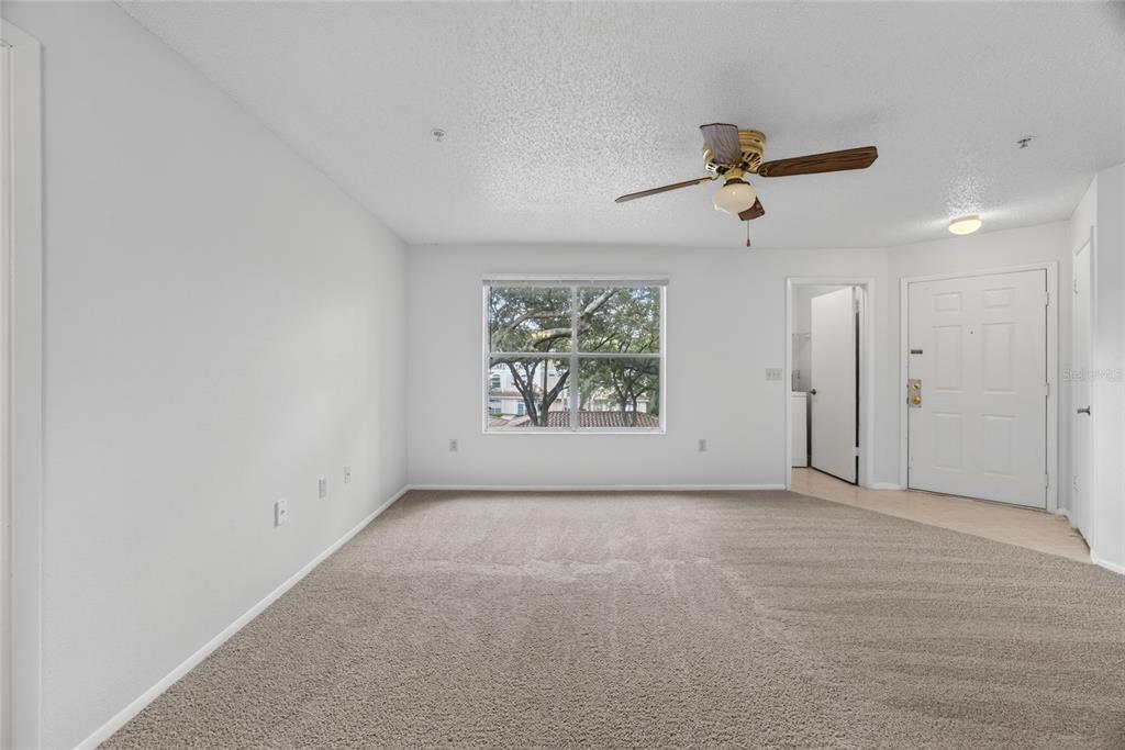 An empty living room features beige carpet, a ceiling fan, and a white entry door — 642 DORY LANE UNIT 203, ALTAMONTE SPRINGS, FL
