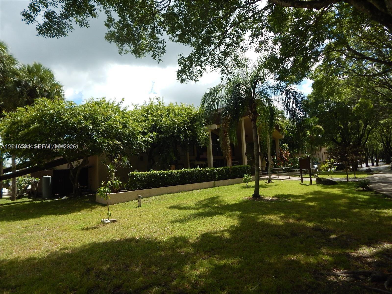 A low-rise building with a covered entrance sits behind a manicured lawn and trees — 14601 N Kendall Dr # 304K, Miami FL 33186, MIAMI, FL