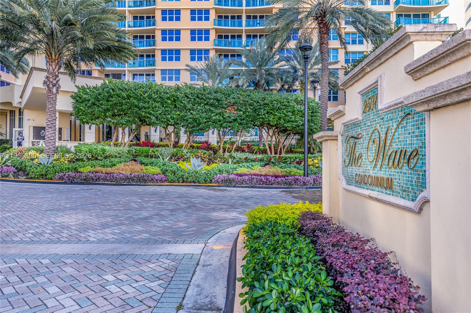 The exterior of a condominium building features a paved driveway, lush landscaping, and a sign — 2501 S Ocean Dr # 439, Hollywood FL 33019, HOLLYWOOD, FL