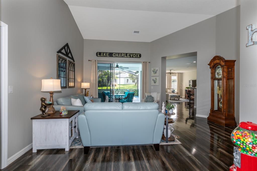 A living room features light blue sofas, a grandfather clock, and a view of a patio — 5110 RIVER EDGE LANE, LEESBURG, FL