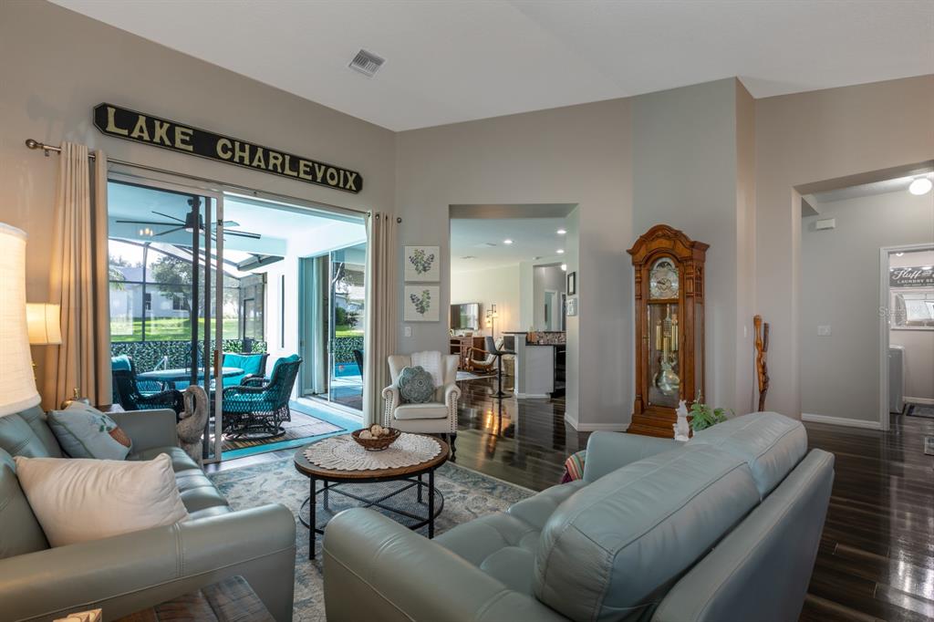 A living room features blue leather sofas, a grandfather clock, and a sliding glass door — 5110 RIVER EDGE LANE, LEESBURG, FL