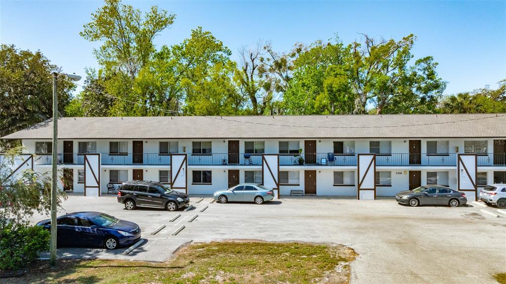 A two-story apartment building with a parking lot in front and mature trees behind — 1216 KENNEDY ROAD, DAYTONA BEACH, FL